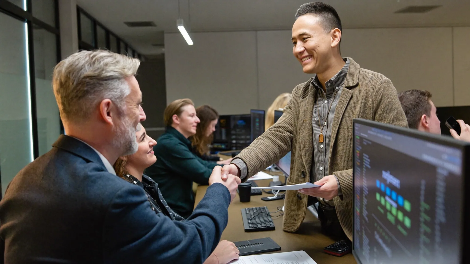 A client shaking hands with a development team, how to choose a custom software development company
