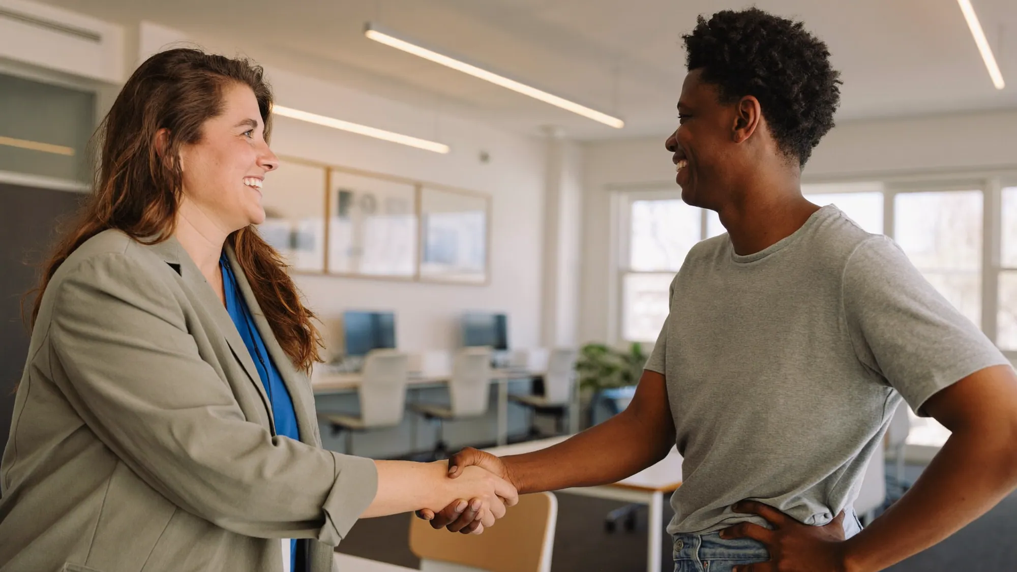 Two team members shaking hands in an office, illustrating nearshore software development rates and fair value