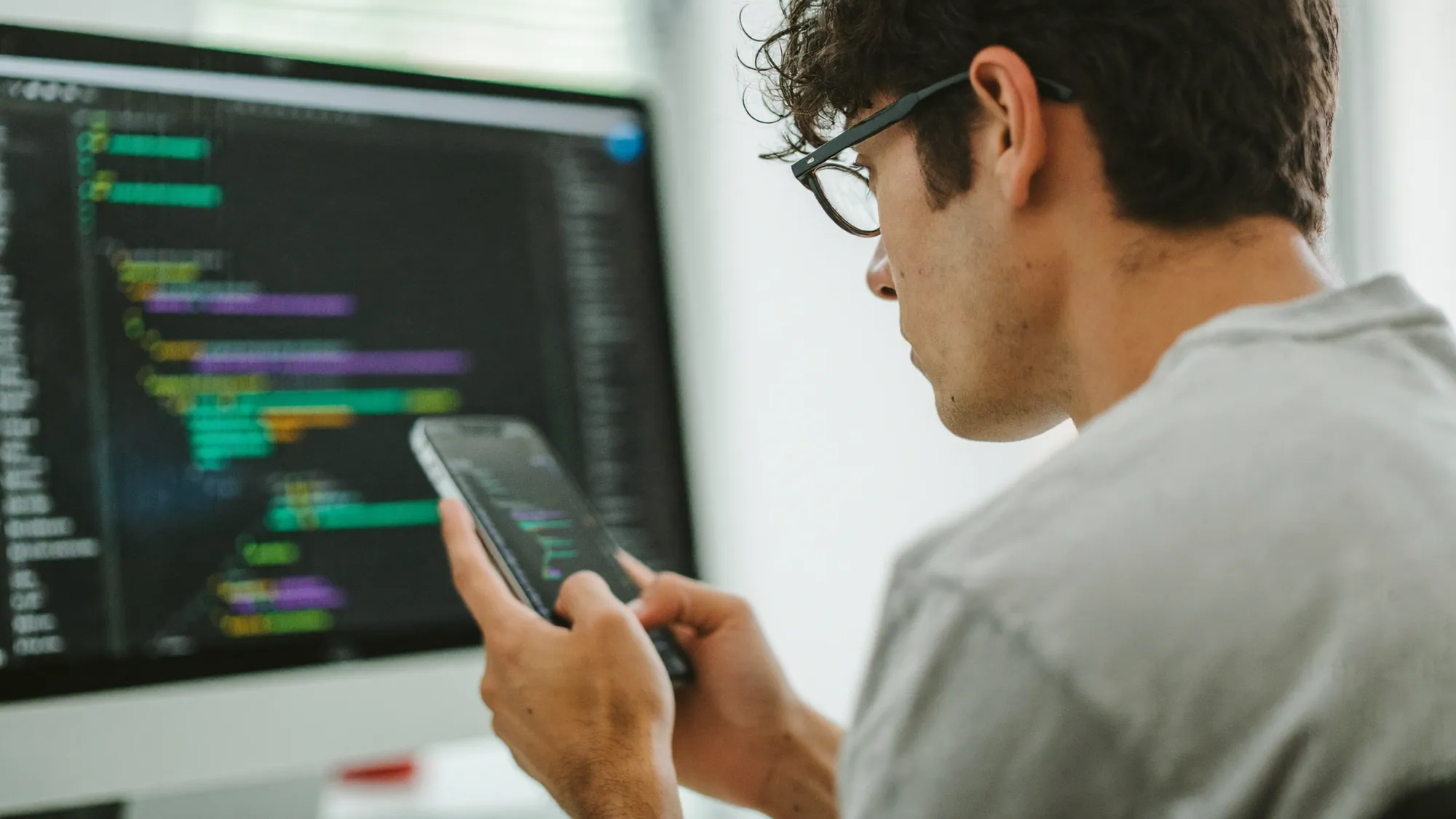 A developer holding a smartphone with code on screen, illustrating what mobile app development is