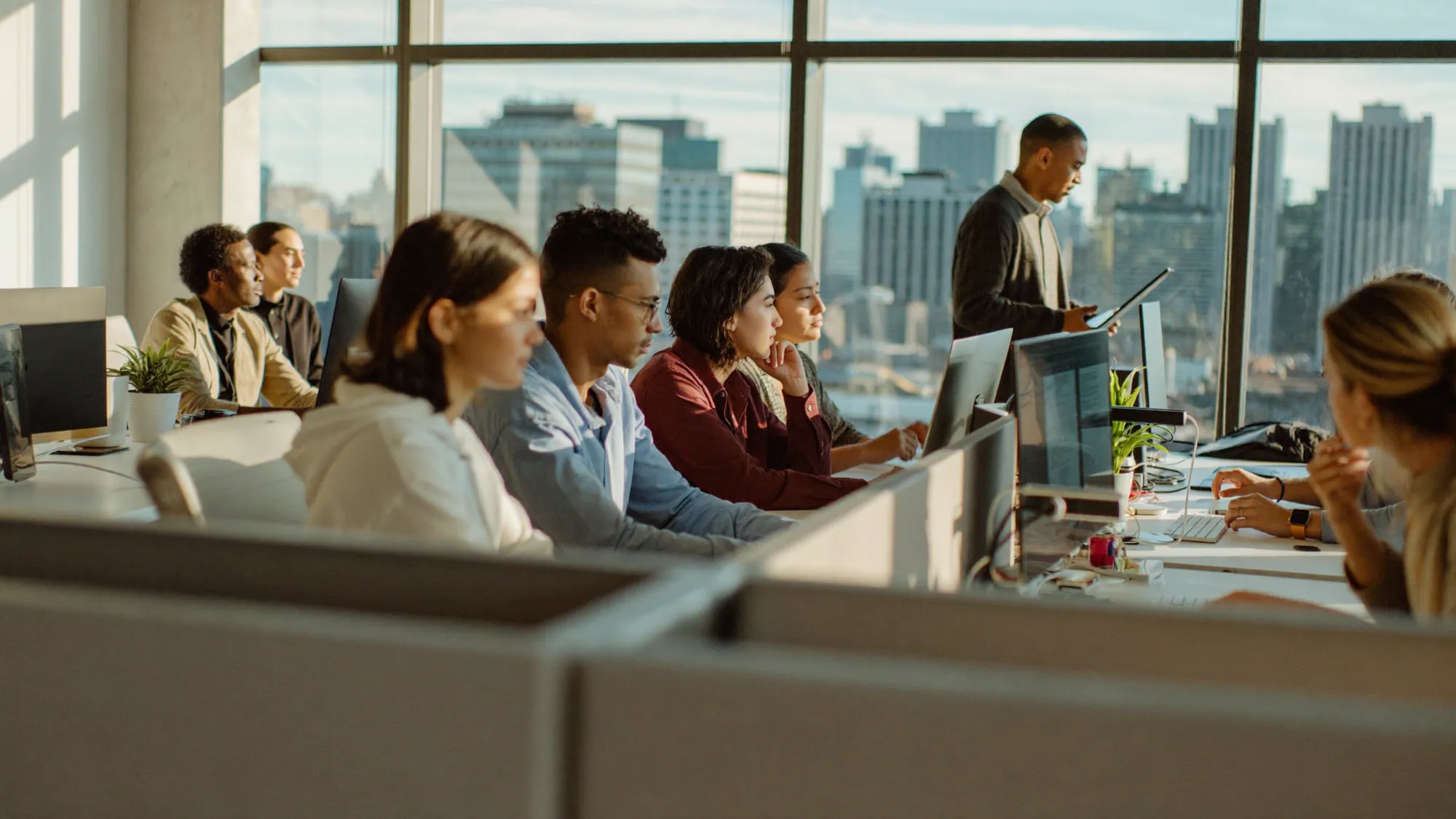 A diverse web development team in a modern office with a Texas city skyline, a nearshore web development company serving Texas and Monterrey