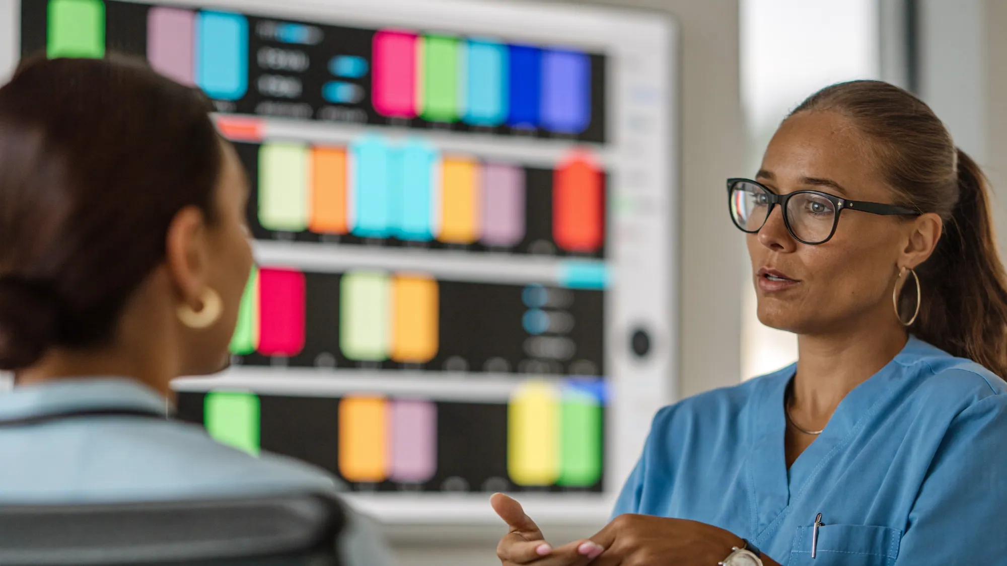 Two healthcare professionals discussing a clinical analytics dashboard of patient outcomes and readmission risk
